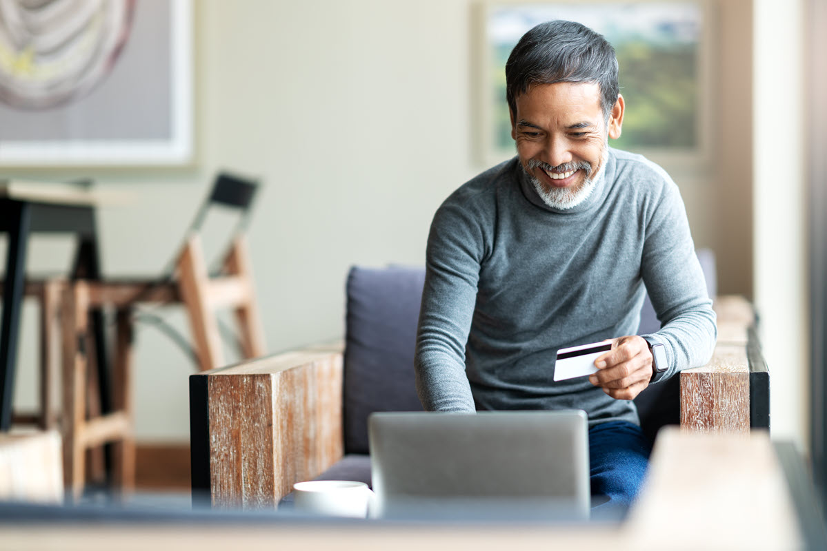 older man in front of computer with credit card